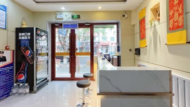 A hotel reception area with a marble counter, a Pepsi vending machine, and a glass door leading outside.