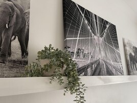 Una pared con tres cuadros: un elefante en blanco y negro, un puente y un paisaje.