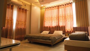 A bedroom with a bed, bedside tables, a ceiling fan, and curtains. - Hotel Bholenath (Khandwa)