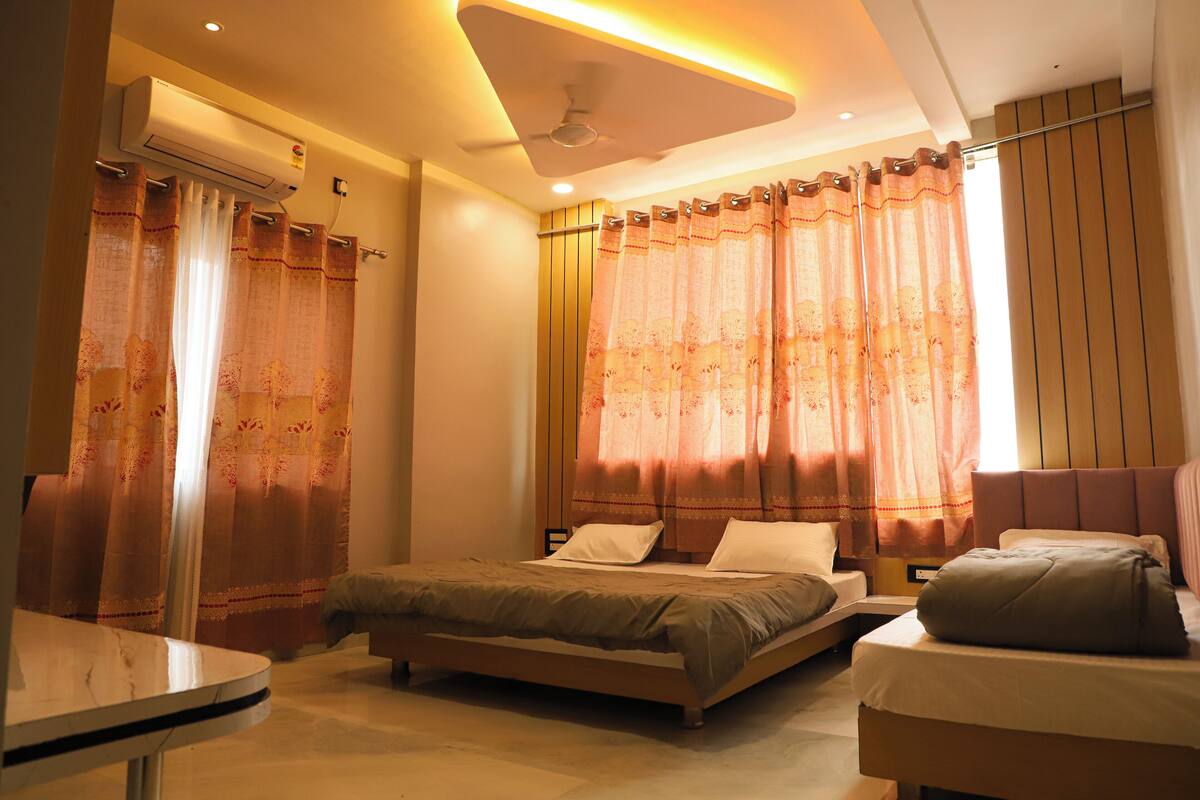 A bedroom with a bed, bedside tables, a ceiling fan, and curtains.