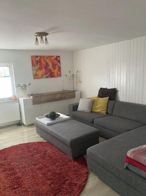 Relax in this stylish living room with a comfortable sofa, vibrant artwork, and a cozy potted plant.