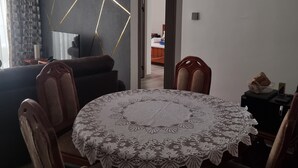 A dining area with a round table covered in lace, surrounded by wooden chairs. - Safari City Two Bedroom Apartment (Nairobi)