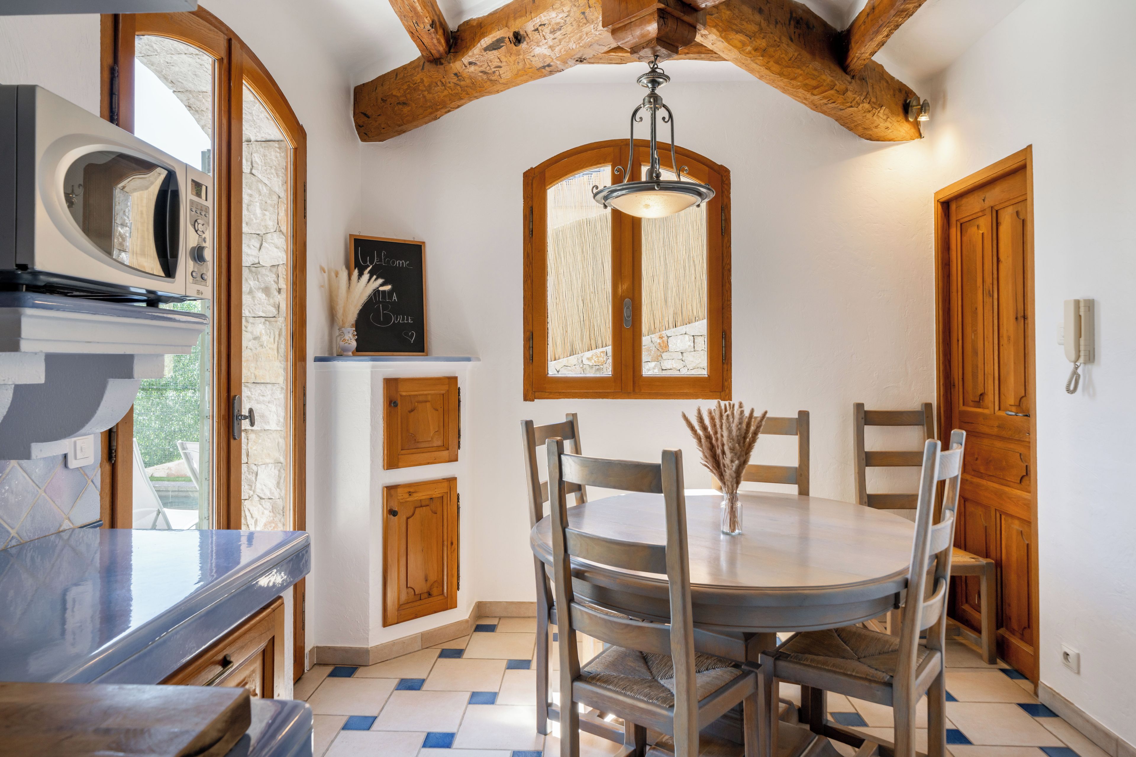 Een keuken met een ronde tafel, houten stoelen, een hanglamp en een stenen muur.