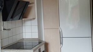 A compact kitchen with a built-in oven, a white refrigerator, and a wooden ceiling. - Beautiful town house with room for 5 people close to the center of Nykøbing Mors (Nykøbing Mors)