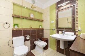 Un baño con inodoro, bidé, lavabo y espejo.