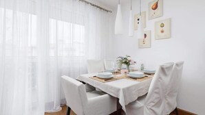 En matplats med ett bord dukat för två personer, vita stolar, en vit duk och en vas med blommor.