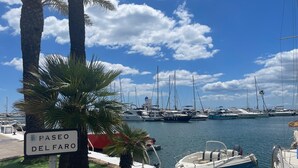 Ein Yachthafen mit verschiedenen Booten, Palmen und einem Schild mit der Aufschrift 'PASEO DEL FARO'.