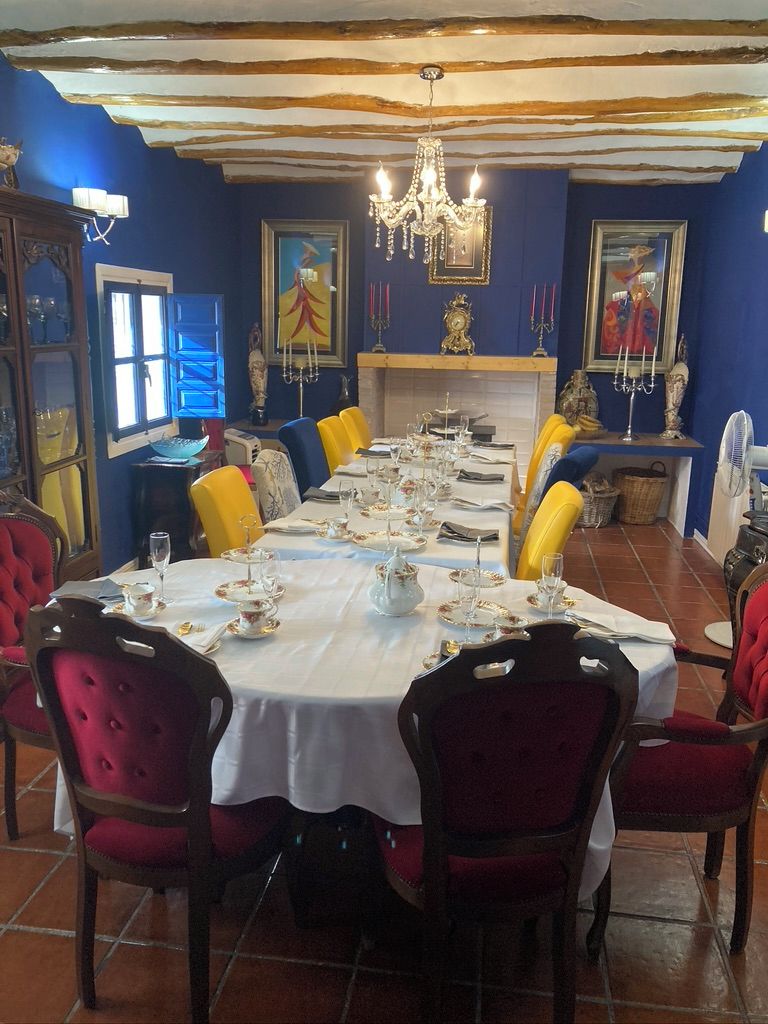 A dining room with a long table set for a meal, surrounded by red upholstered chairs.
