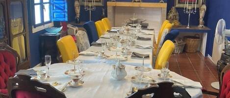 A dining room with a long table set for a meal, surrounded by red upholstered chairs.
