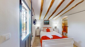 A bedroom with a bed, bedside tables, a window, and a bathroom visible through an open door. - Casa Lucia (Caniles)