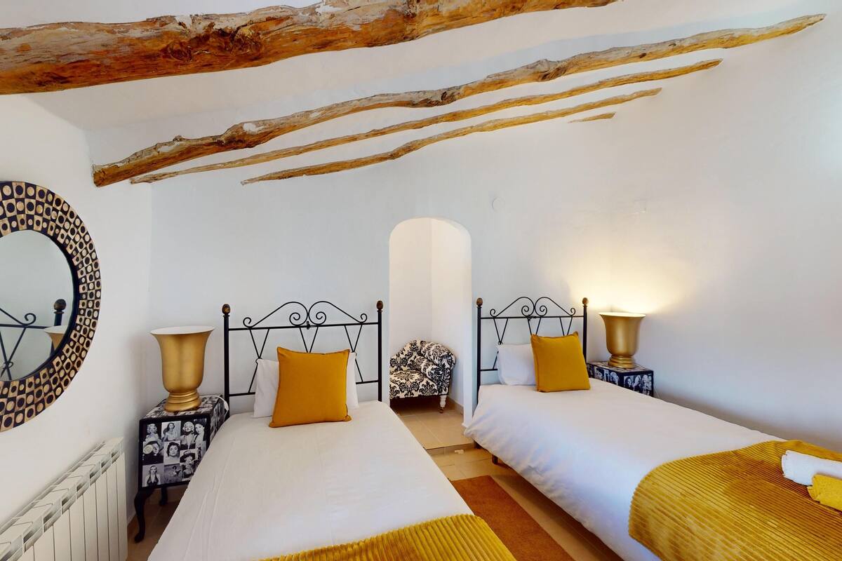 A bedroom with two beds, a large mirror, and a unique ceiling design.