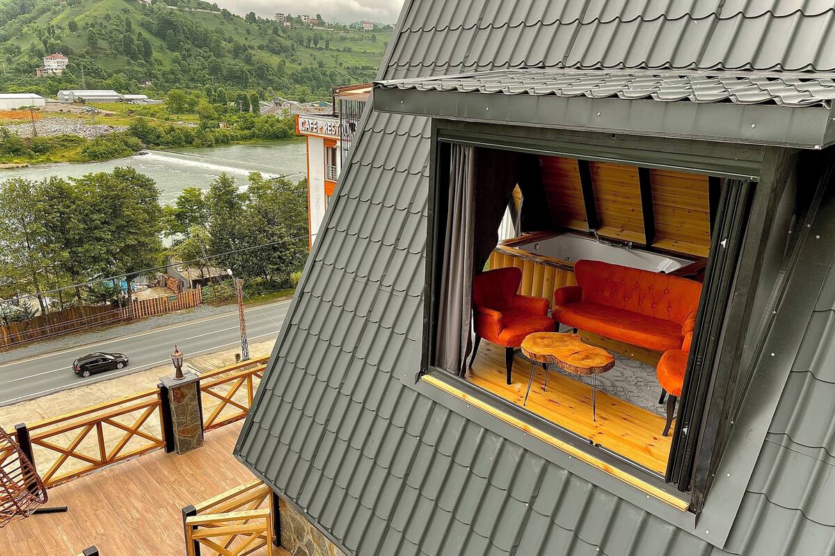 Une chambre avec vue sur une rivière, un coin repas avec une table et des chaises, et un balcon doté de balustrades en bois.