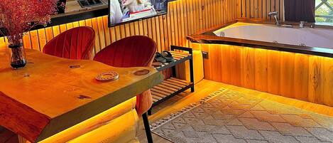 A cozy, wooden interior with a wooden desk, a red chair, a television, and a large window.