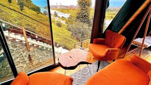 Une pièce moderne dotée de grandes fenêtres, de chaises orange et d’une table en bois au design original.