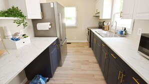 A modern kitchen with white marble countertops, dark cabinets, a stainless steel refrigerator, and a window providing natural light. - 5 min Walk to Notre Dame Modern Home 517 (South Bend)