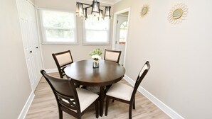 A dining area with a round table, four chairs, a chandelier, and two windows with blinds. - 5 min Walk to Notre Dame Modern Home 517 (South Bend)