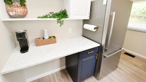 A kitchen with a marble countertop, a coffee maker, a refrigerator, and a shelf with a coffee-themed decoration. - 5 min Walk to Notre Dame Modern Home 517 (South Bend)