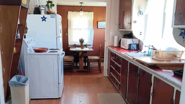 A compact kitchen with a refrigerator, stove, and wooden cabinets. -  Farmhouse sleeps 2 -6  in the Allegheny National Forest outside Bradford Pa (Bradford)