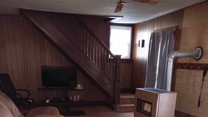 A living room with a large sectional sofa, a television, a fireplace, and a staircase leading to an upper level. -  Farmhouse sleeps 2 -6  in the Allegheny National Forest outside Bradford Pa (Bradford)