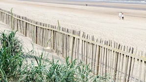 A beach with a wooden fence and some greenery in the foreground. - Mablethorpe Lakeside Caravan With Decking & Wi-fi! (Mablethorpe)