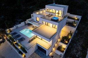 Una casa moderna de varios pisos con piscina, mobiliario de exterior y jacuzzi.