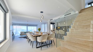 A modern dining area with a glass staircase leading to an upper level. - Villa Oasis (Trogir)