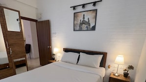 Ein ordentlich bezogenes Bett mit weißen Leinen, einem hölzernen Kopfteil und zwei Nachttischlampen.