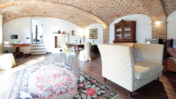 Amplia sala de estar con un techo de ladrillo abovedado, un tapete estampado, un sofá y un mueble de madera.