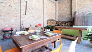 Un área de comedor al aire libre con paredes de ladrillo, mesas y sillas de madera.