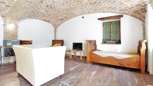 Una habitación con techo de ladrillo, una cama, un sofá blanco, una mesa de madera y un televisor.