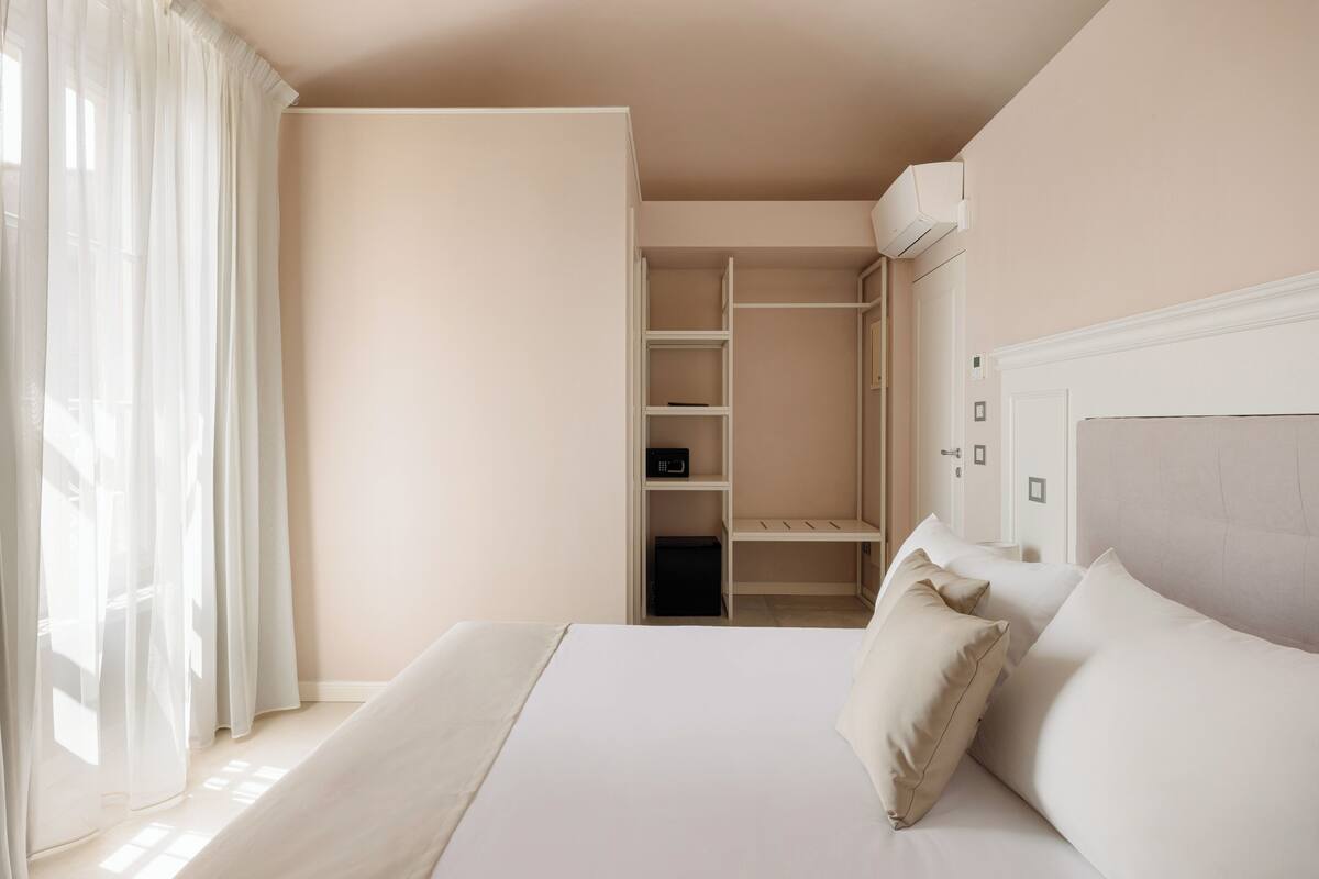 A bedroom with a bed, a closet, and a window with curtains.