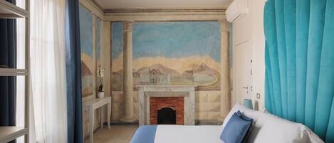 A bedroom with a bed, a fireplace, and a mural on the wall.