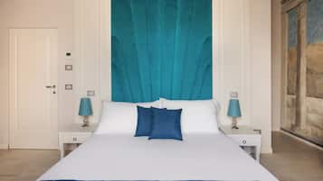 Habitación de hotel con una cama grande, paredes blancas, un cabecero azul turquesa y dos mesitas de noche con lámparas.