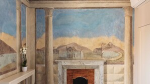 A room with a fireplace, columns, and a mural on the wall. - Prato dei Miracoli Residenza d'Epoca (Pisa)