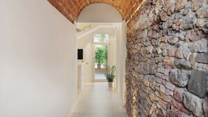 A hallway with a brick archway, a stone wall, and a potted plant. - Prato dei Miracoli Residenza d'Epoca (Pisa)