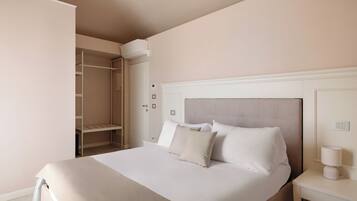 A neatly arranged hotel room with a large bed, a bedside table with a lamp, and a wardrobe with a hanging organizer.