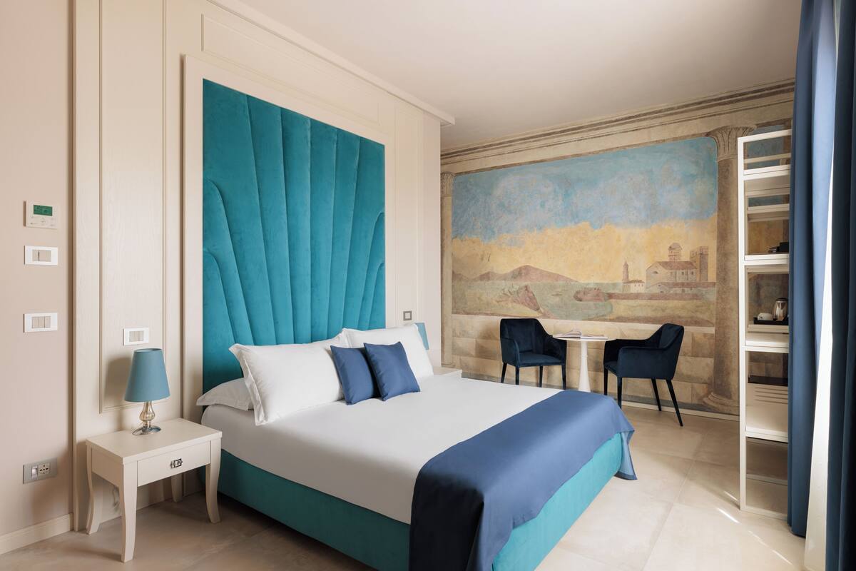 A hotel room with a large bed, a nightstand, a desk, and a chair.
