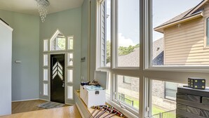A room with a wooden floor, a white door with a black frame, a white chest of drawers, and a window with a view of a brick building and greenery. - Exquisite Canal-front Home: Access to Lake Conroe! (Montgomery)