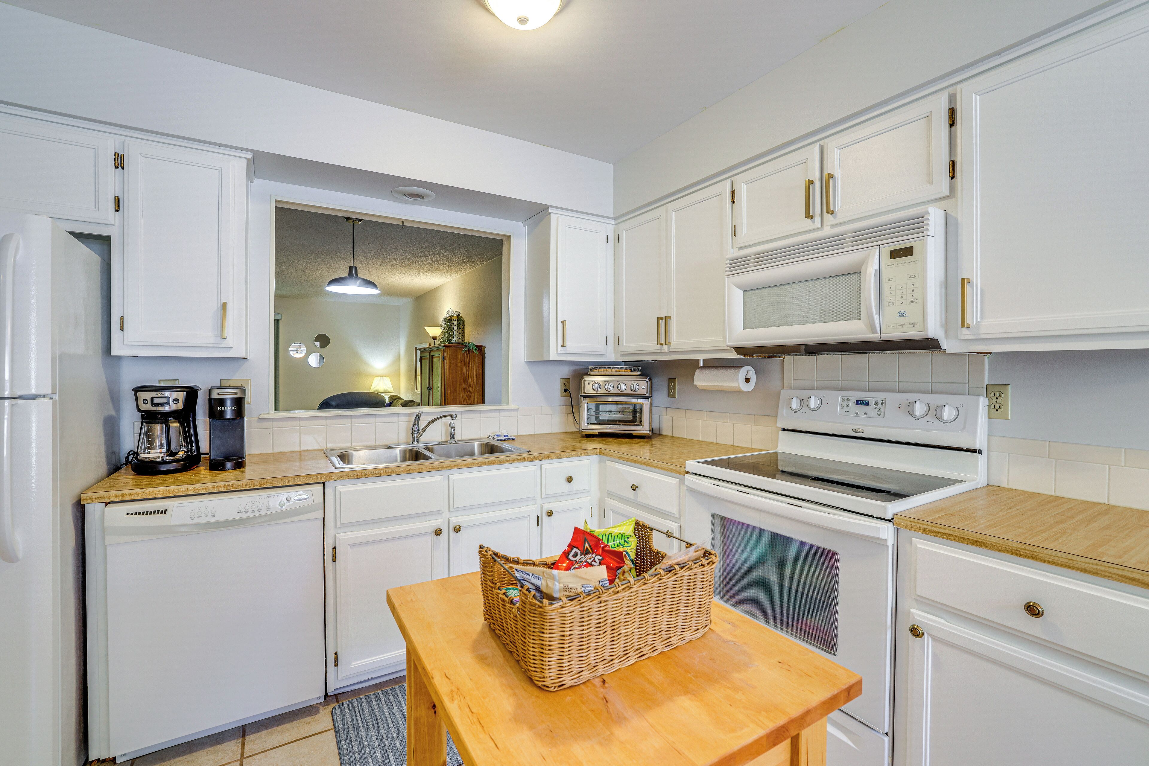 A kitchen with white cabinets, a microwave, an oven, a toaster, and a dishwasher.