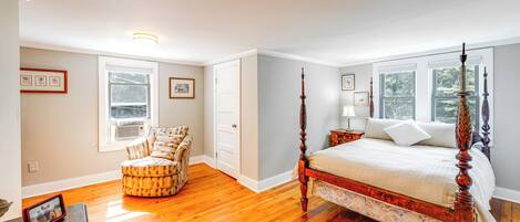 A bedroom with a four-poster bed, a chair, and a nightstand.