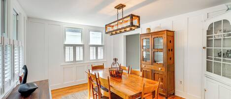 A dining room with a wooden table and chairs, a chandelier, and a cabinet with glass doors.