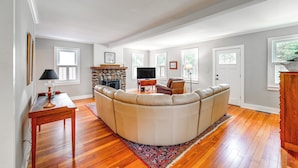 A spacious living room with a large L-shaped sectional sofa, a flat-screen TV, and a stone fireplace. - 2 Mi to Dtwn: 2-acre Retreat w/ Large Yard! (Madison)