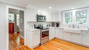 A modern kitchen with white cabinets, stainless steel appliances, and a wooden floor. - 2 Mi to Dtwn: 2-acre Retreat w/ Large Yard! (Madison)