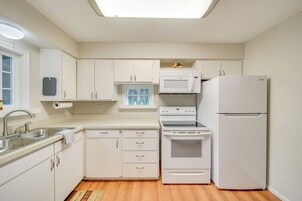 A compact kitchen with white cabinets, a built-in oven, a microwave, and a refrigerator.