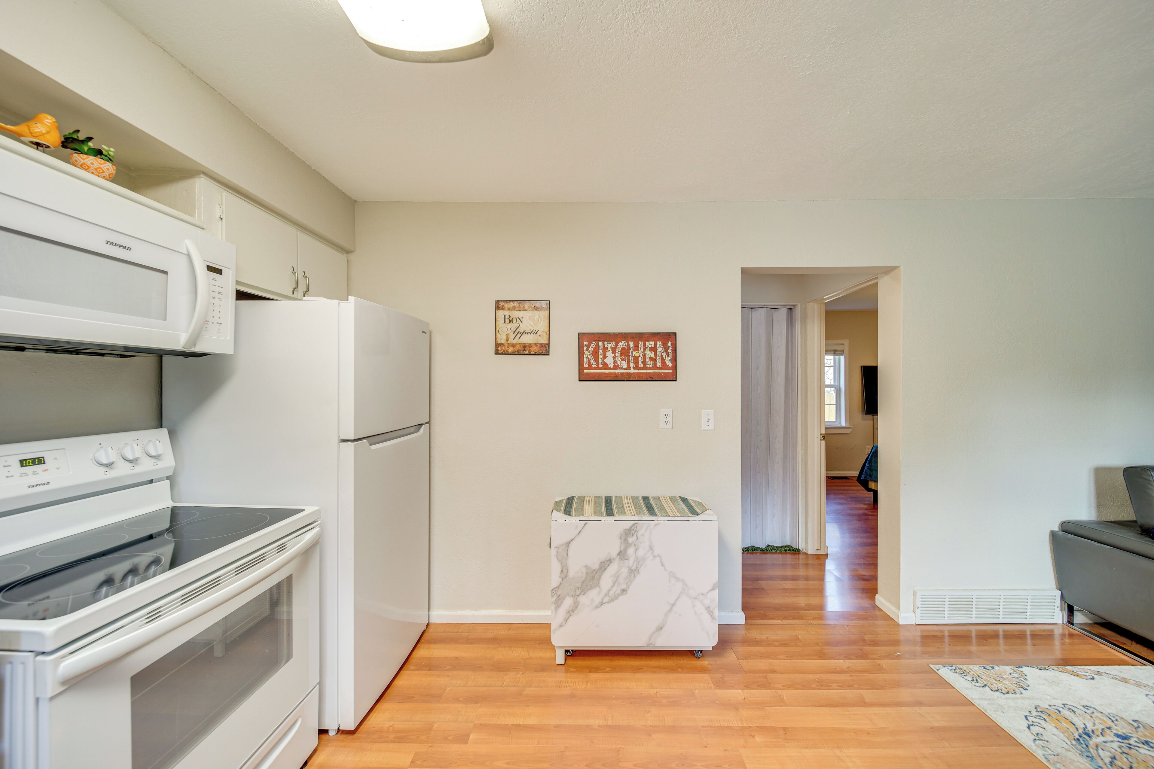 A kitchen with a microwave, stove, and refrigerator. There is a marble island and a sign that says "KITCHEN".
