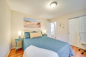 A bedroom with a bed, nightstands, a painting, and a door.