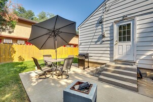 A patio with a table and chairs, a large umbrella, and a fire pit.