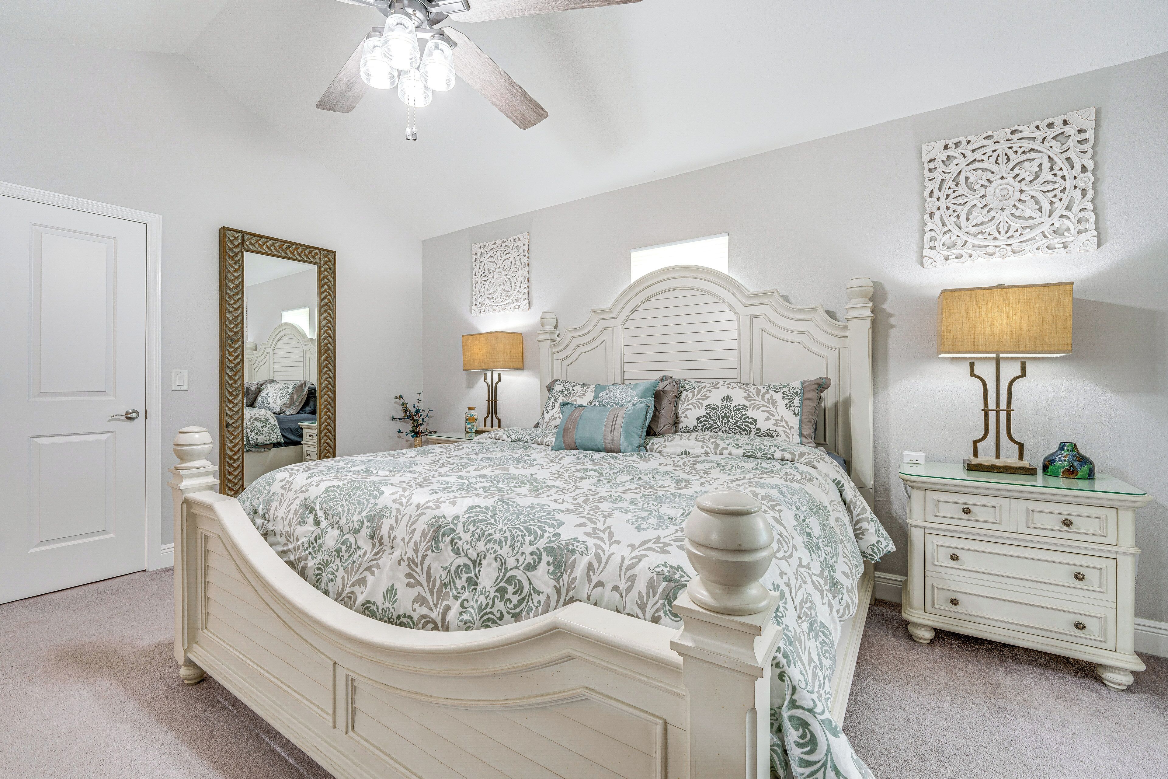 A bedroom with a bed, dresser, nightstand, and a ceiling fan.