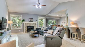 A spacious living room with a fireplace, a ceiling fan, and a dining area with chairs and a table. - Deck & Greenbelt Access: Lovely Austin Home (Austin)
