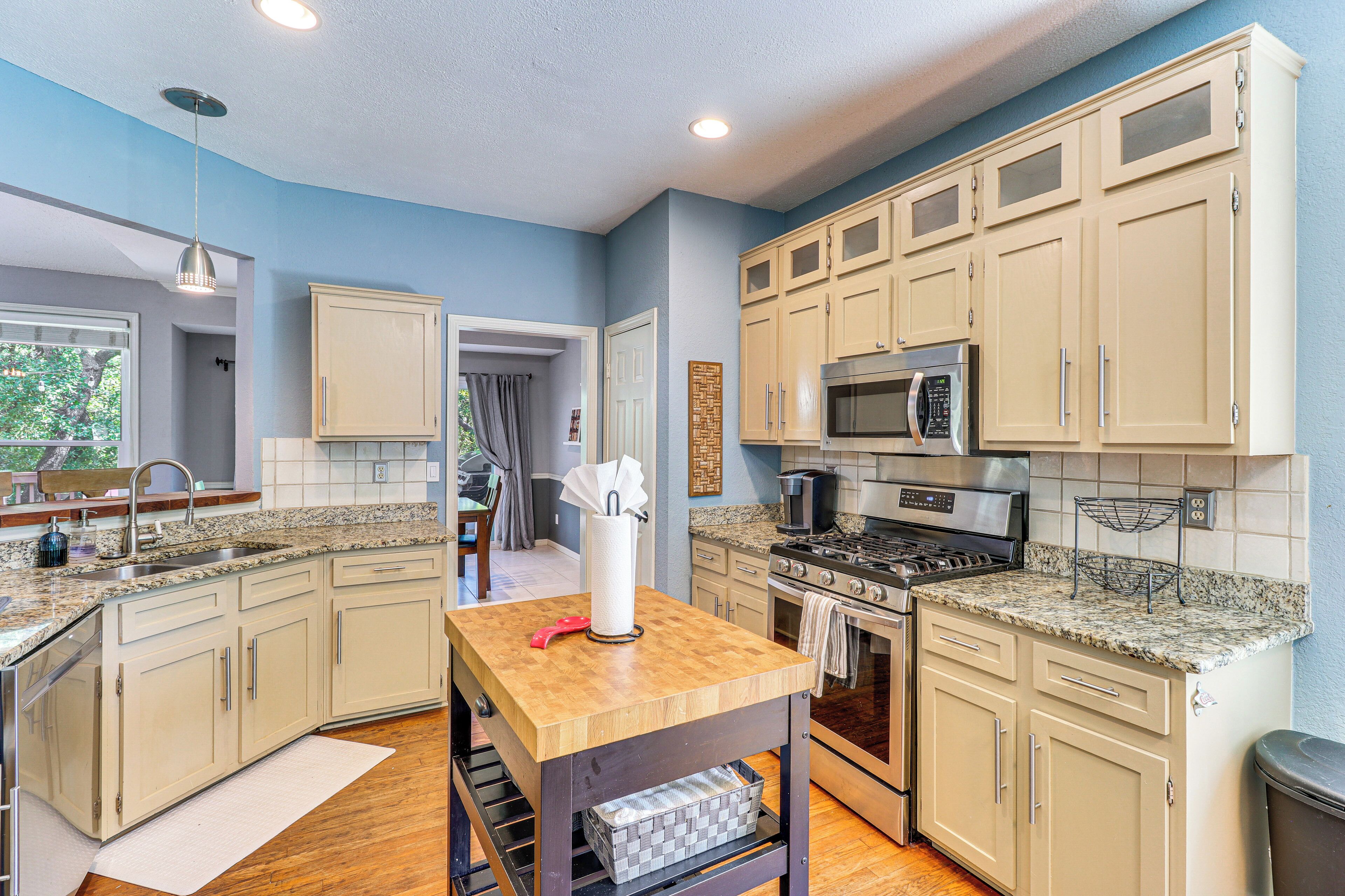 Una cocina con armarios color crema, encimeras de granito, electrodomésticos de acero inoxidable y una isla de madera.